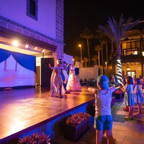a group of children are dancing on a stage at night