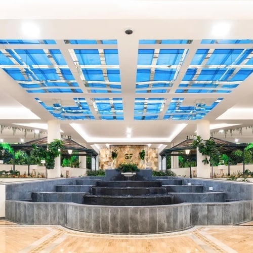 una fuente en un lobby con un techo de vidrio azul