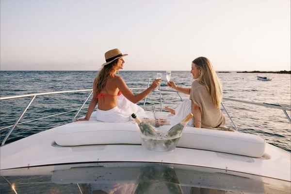 dos mujeres brindan con champán en un barco en el océano
