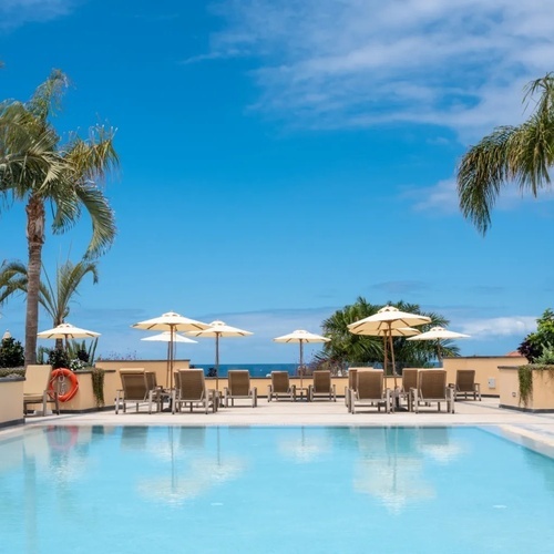 una piscina rodeada de sillas y sombrillas en un día soleado