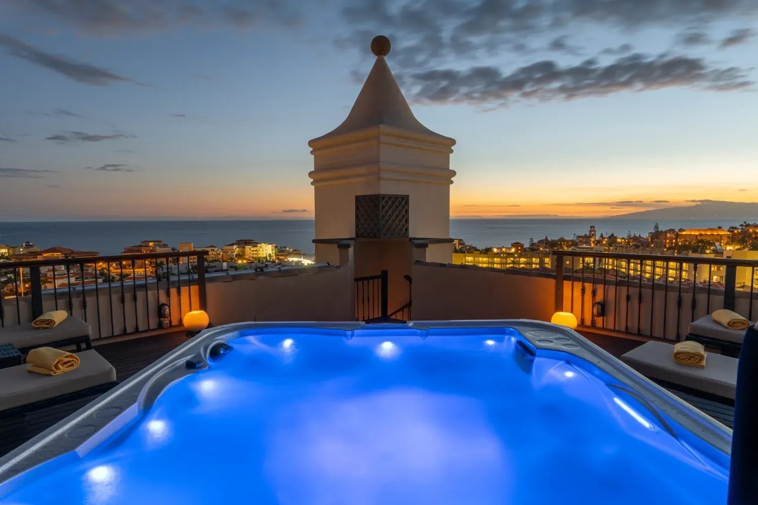 una bañera de hidromasaje en una terraza con vista al océano al atardecer