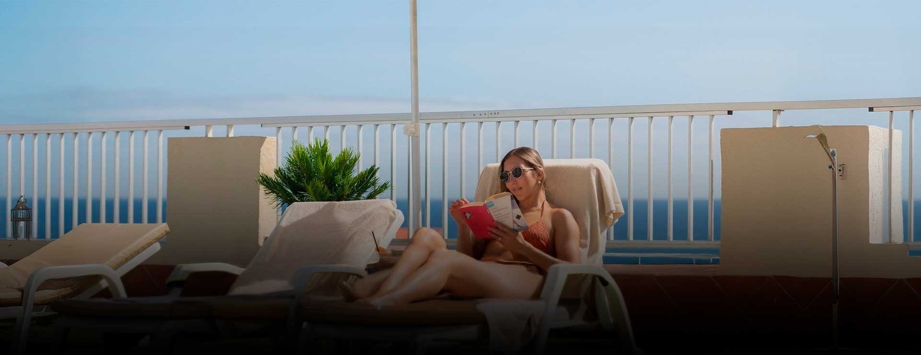 a woman wearing sunglasses and a white dress sits on the beach
