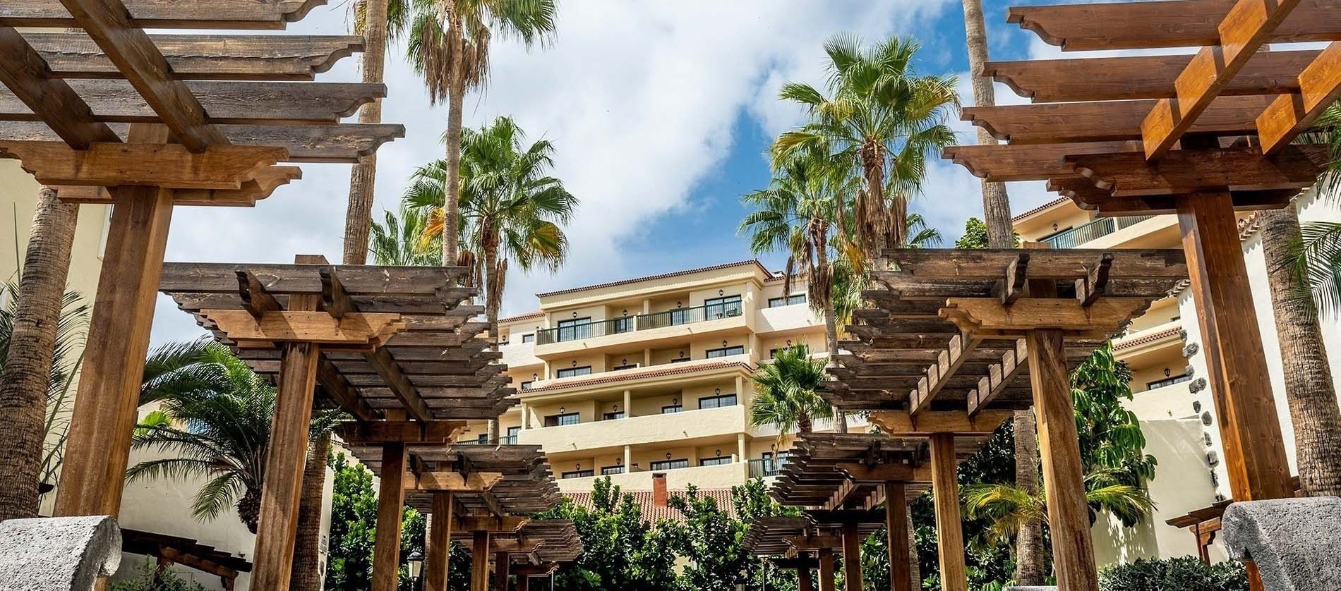 un edificio de apartamentos con palmeras y pergolas de madera