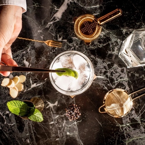 un barman prepara un cóctel en una mesa de mármol