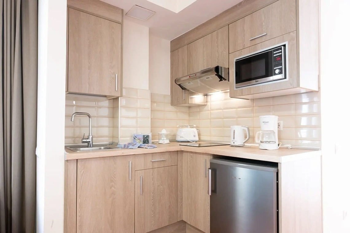 una pequeña cocina con gabinetes de madera y electrodomésticos de acero inoxidable