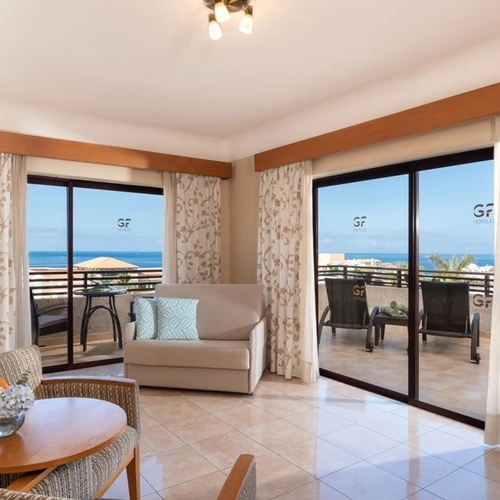 a hotel room with a couch and chairs and a balcony