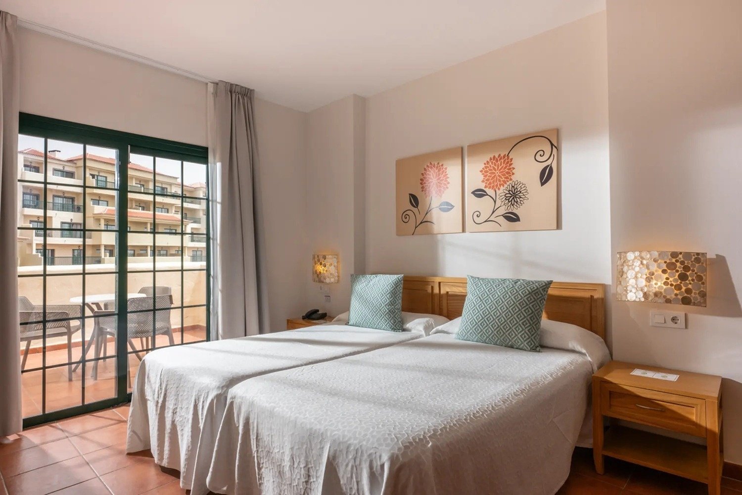 una habitación con dos camas y dos cuadros de flores en la pared