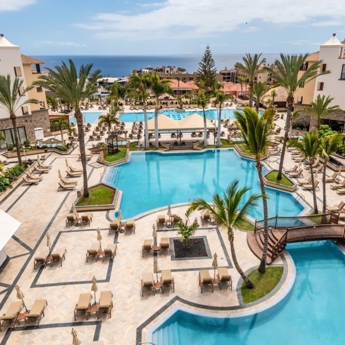 una gran piscina rodeada de palmeras en un resort