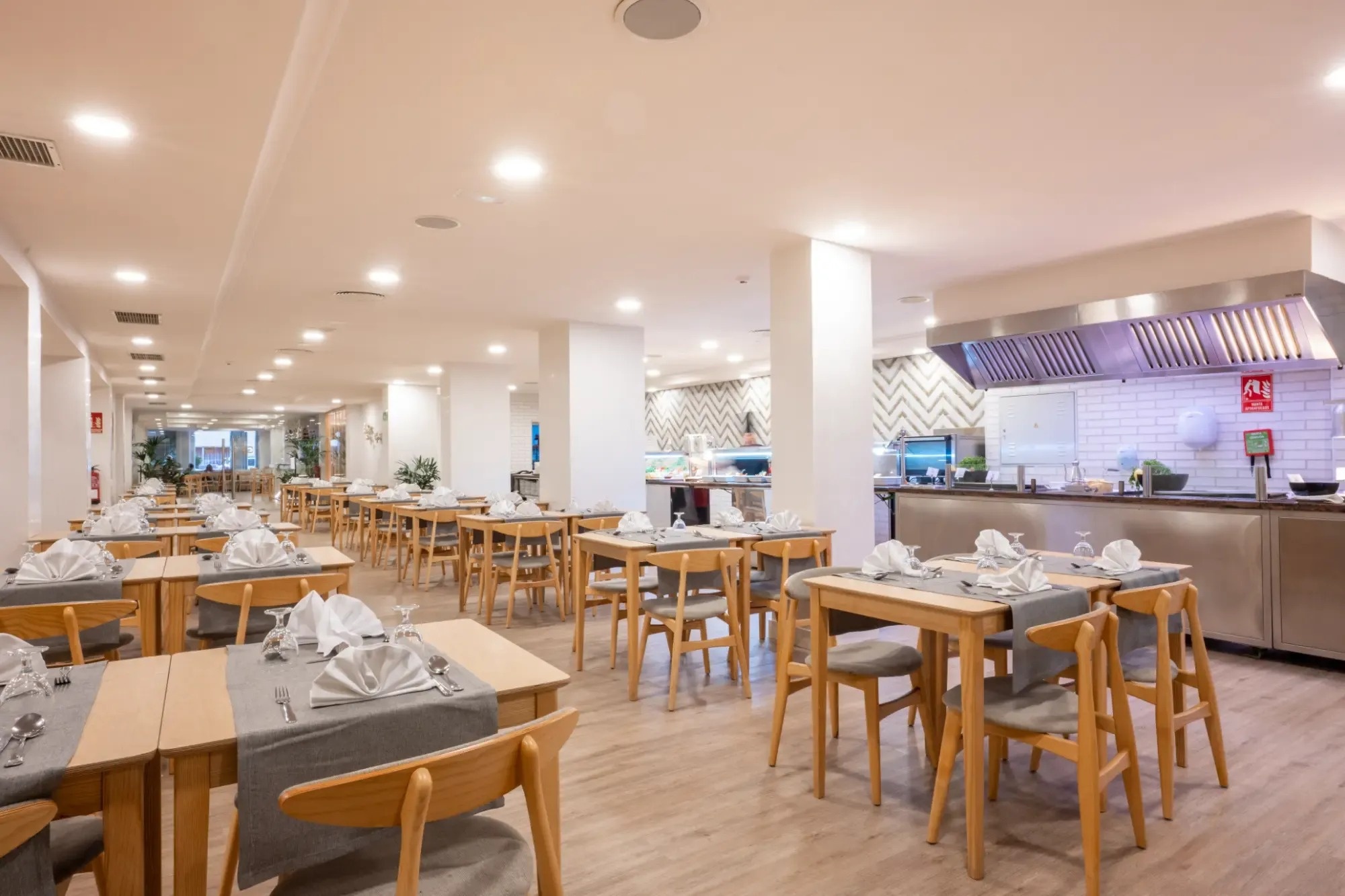 un restaurante lleno de mesas y sillas con una señal de extintor en la pared