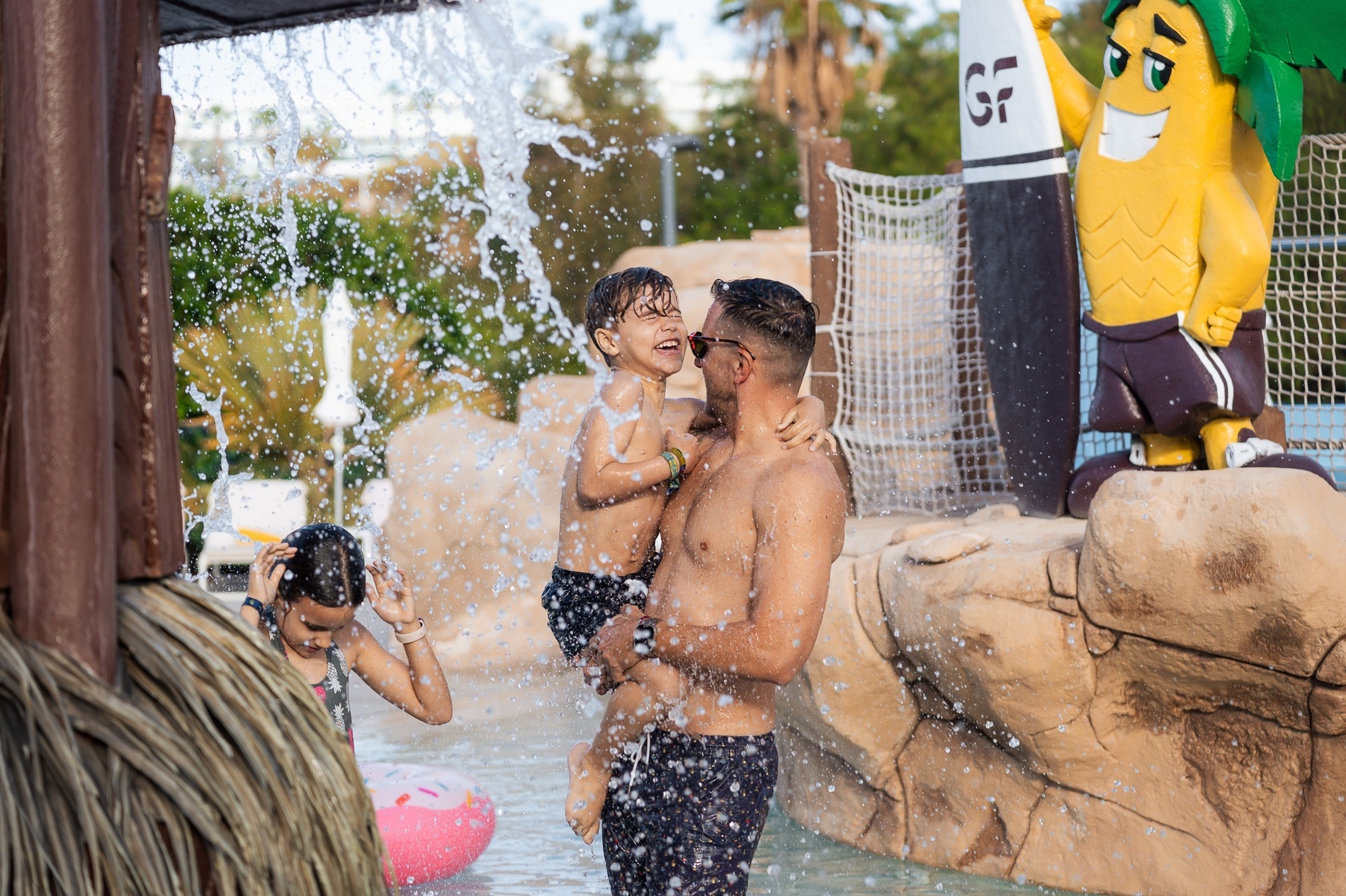 a man holding a child in front of a banana mascot with the letter gf on it
