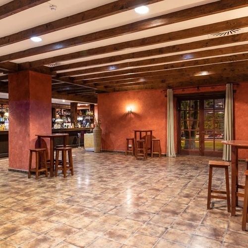 an empty room with tables and stools in front of a bar