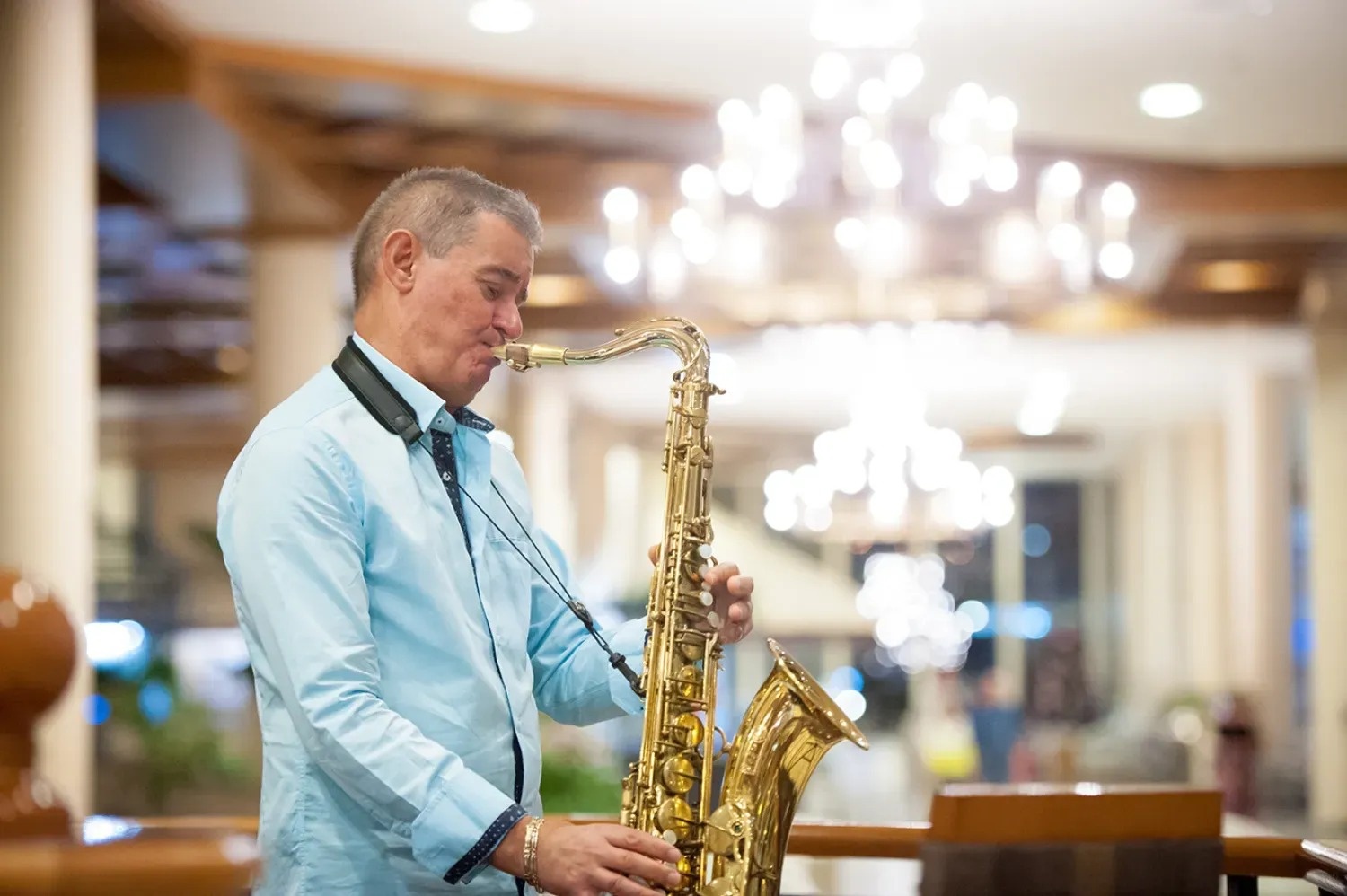 a man in a blue shirt is playing a saxophone