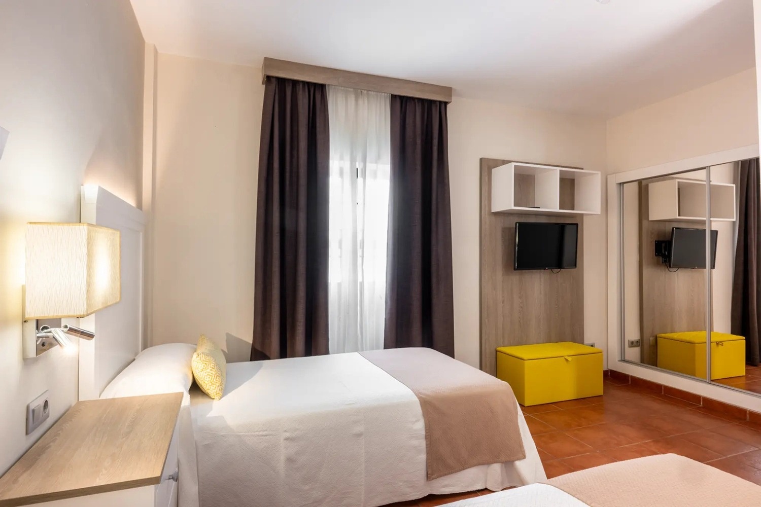 una habitación con una cama y un televisor en la pared