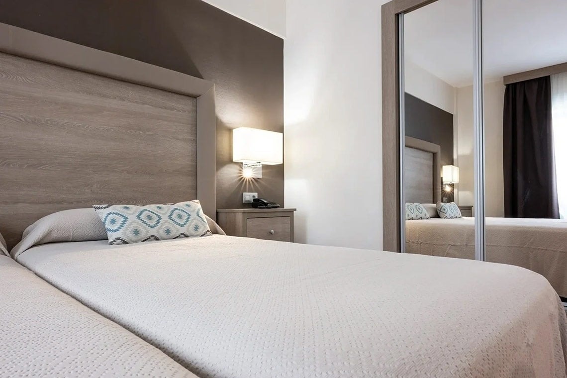 una habitación con dos camas y un espejo