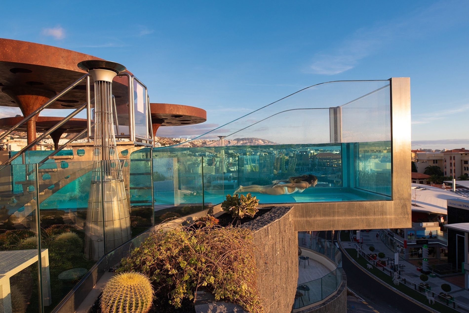 una mesa con comida y una botella de vino frente a una piscina al atardecer