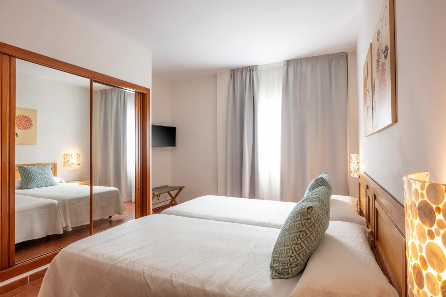 una habitación con dos camas y una televisión en la pared