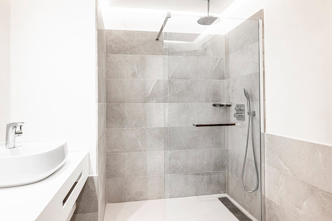 un baño con un lavabo y una ducha con una puerta de vidrio