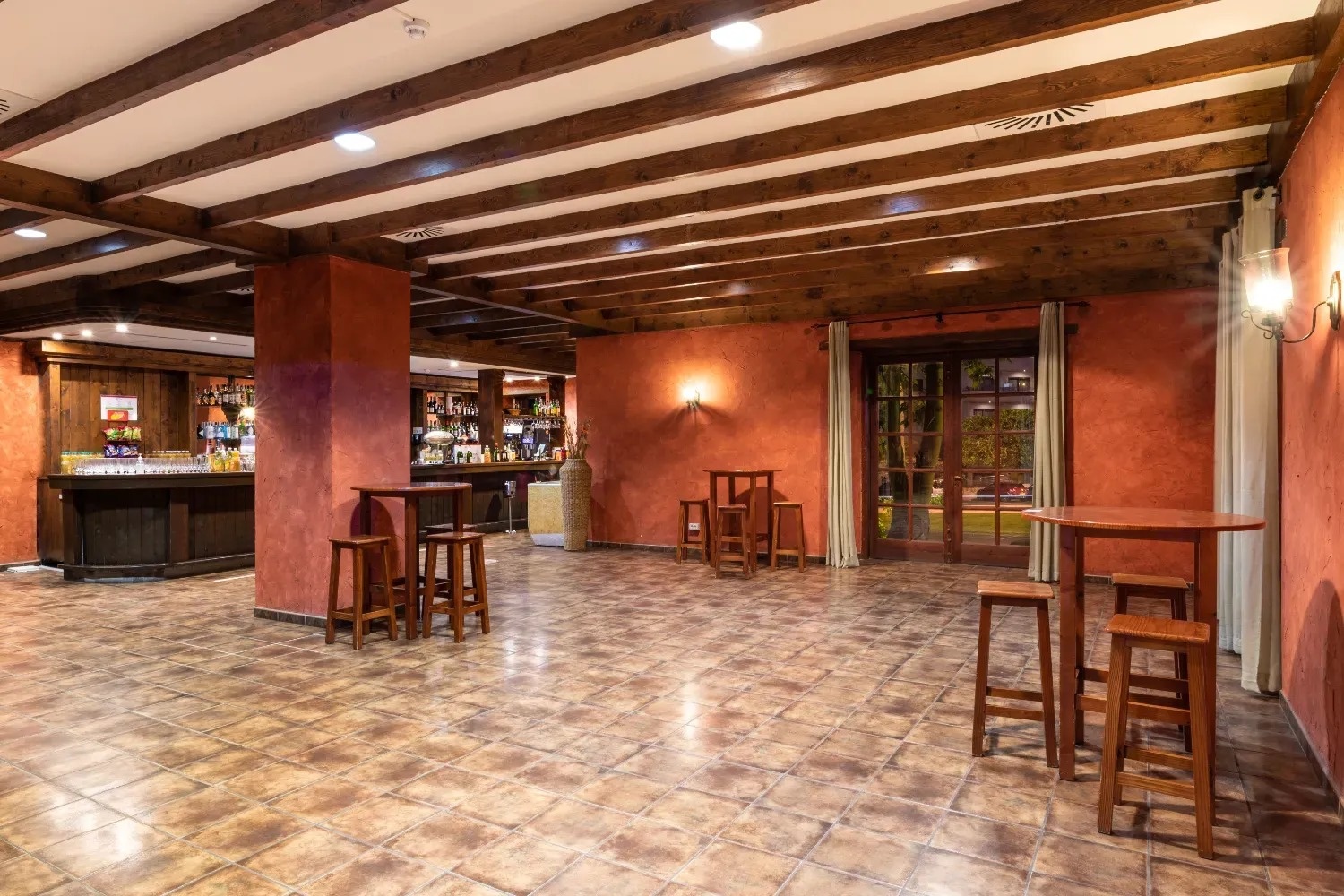 una habitación llena de mesas y taburetes con un bar en el fondo