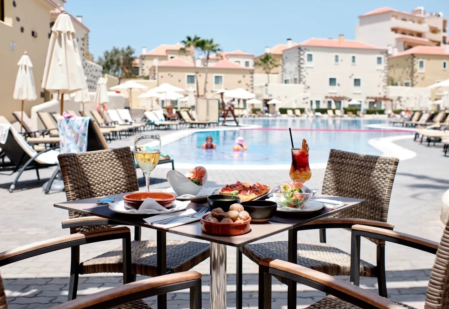 una mesa con comida y bebidas frente a una piscina
