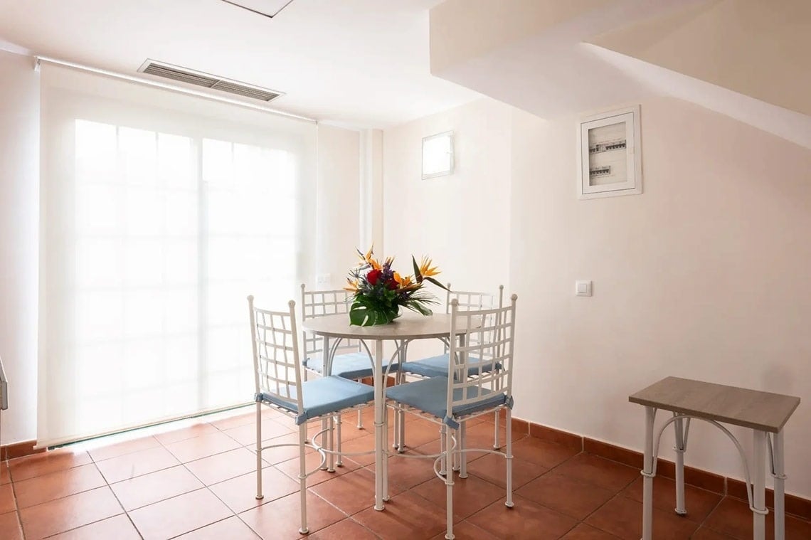 una habitación con una mesa y sillas y un jarrón de flores