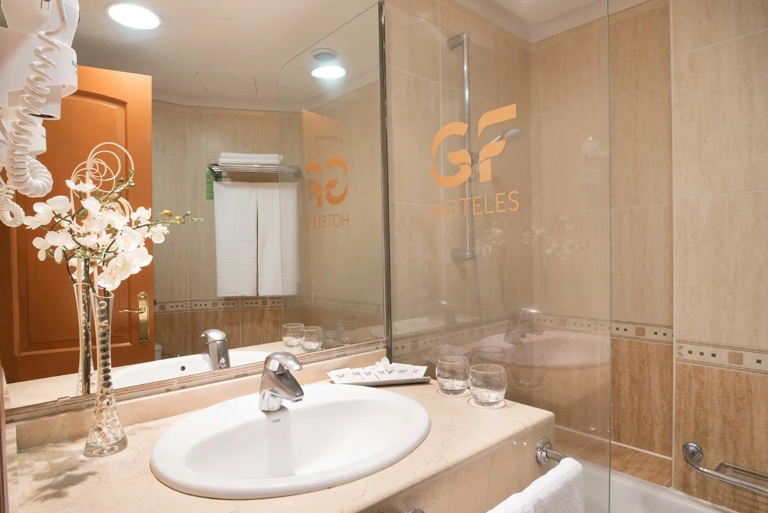 un baño con un lavabo y un espejo con la palabra hoteles en la pared