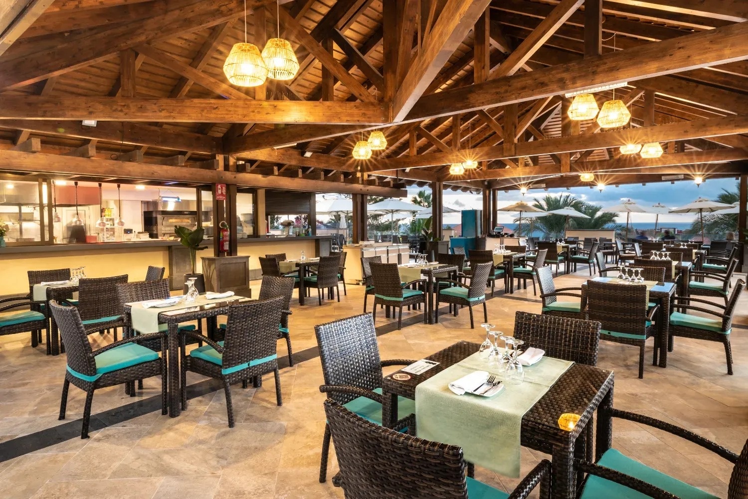 a restaurant with tables and chairs under a wooden roof