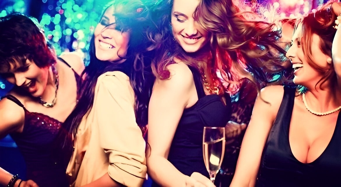 a group of women are dancing and one is holding a glass of champagne