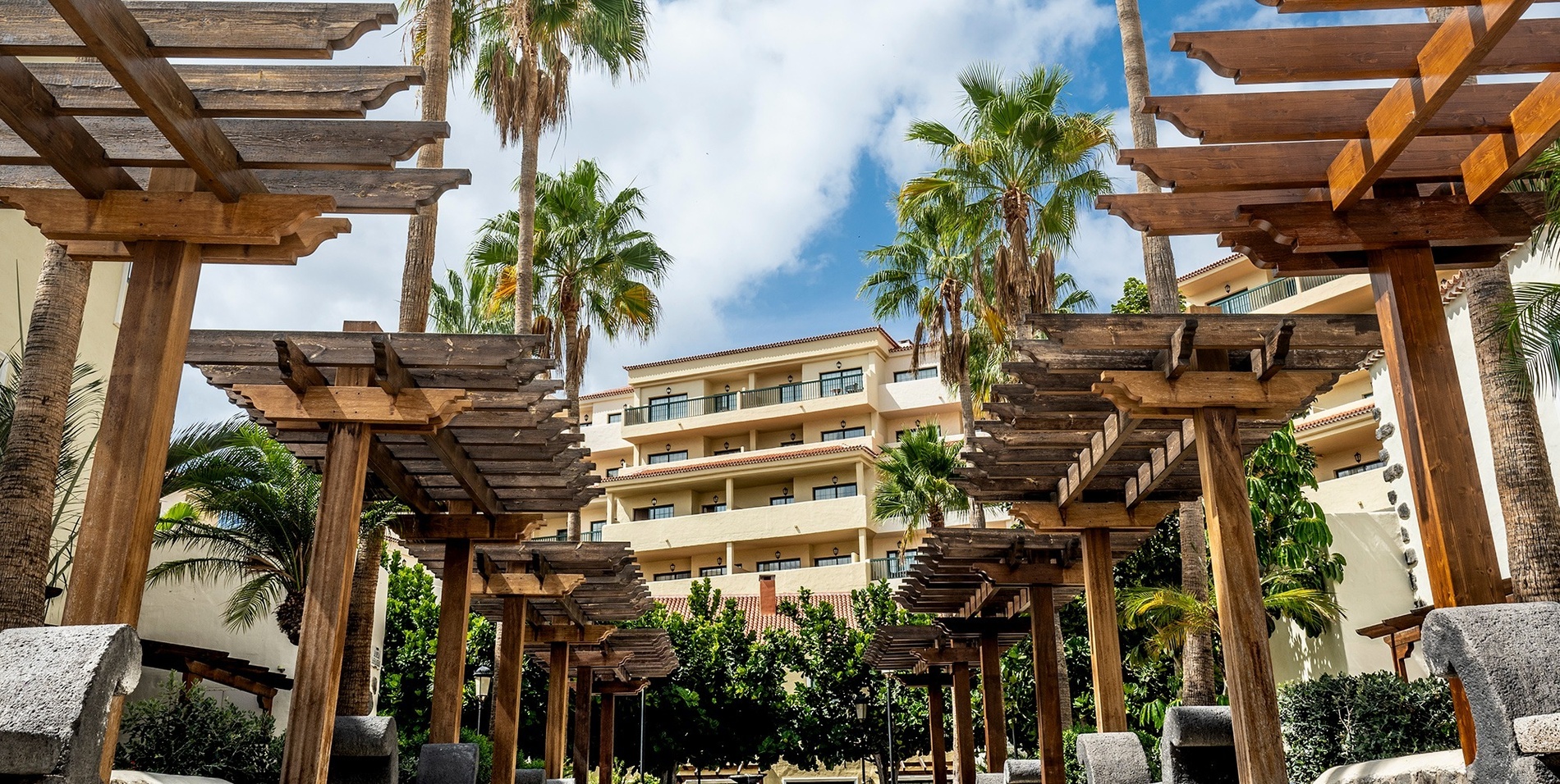 un edificio de apartamentos con palmeras y pergolas de madera