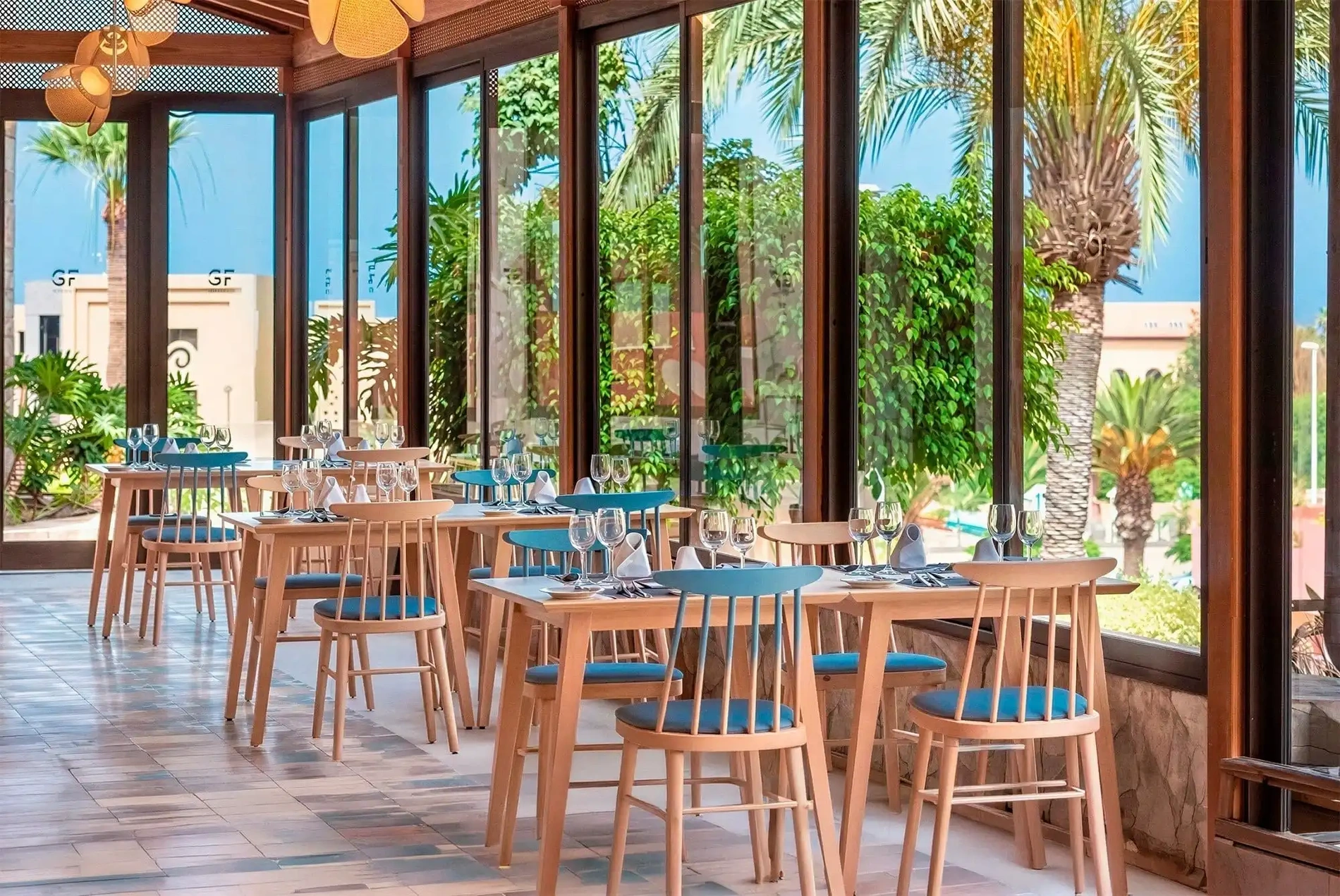 Bright restaurant with set tables and palm views. Book Early Booking | GF Gran Costa Adeje.