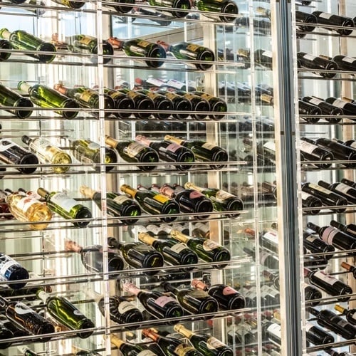 un montón de botellas de vino están en un estante de vidrio