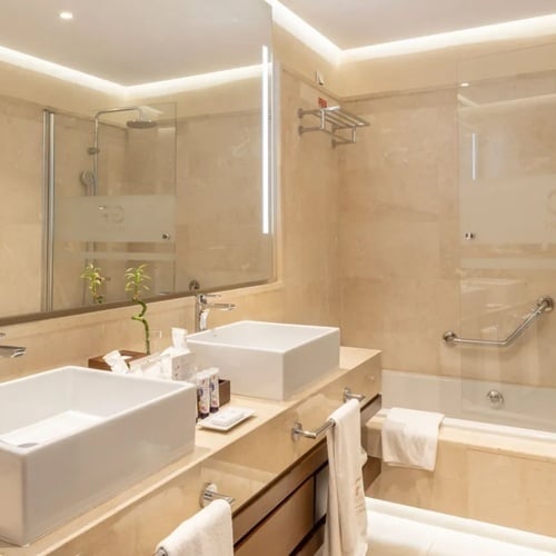 un baño de hotel con dos lavabos y una bañera