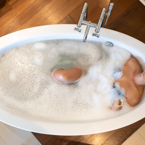 una mujer se relaja en una bañera llena de espuma y sostiene una copa de champán