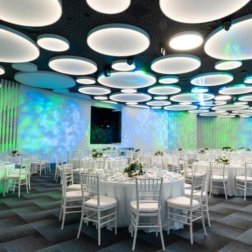 una habitación llena de mesas y sillas con luces en el techo