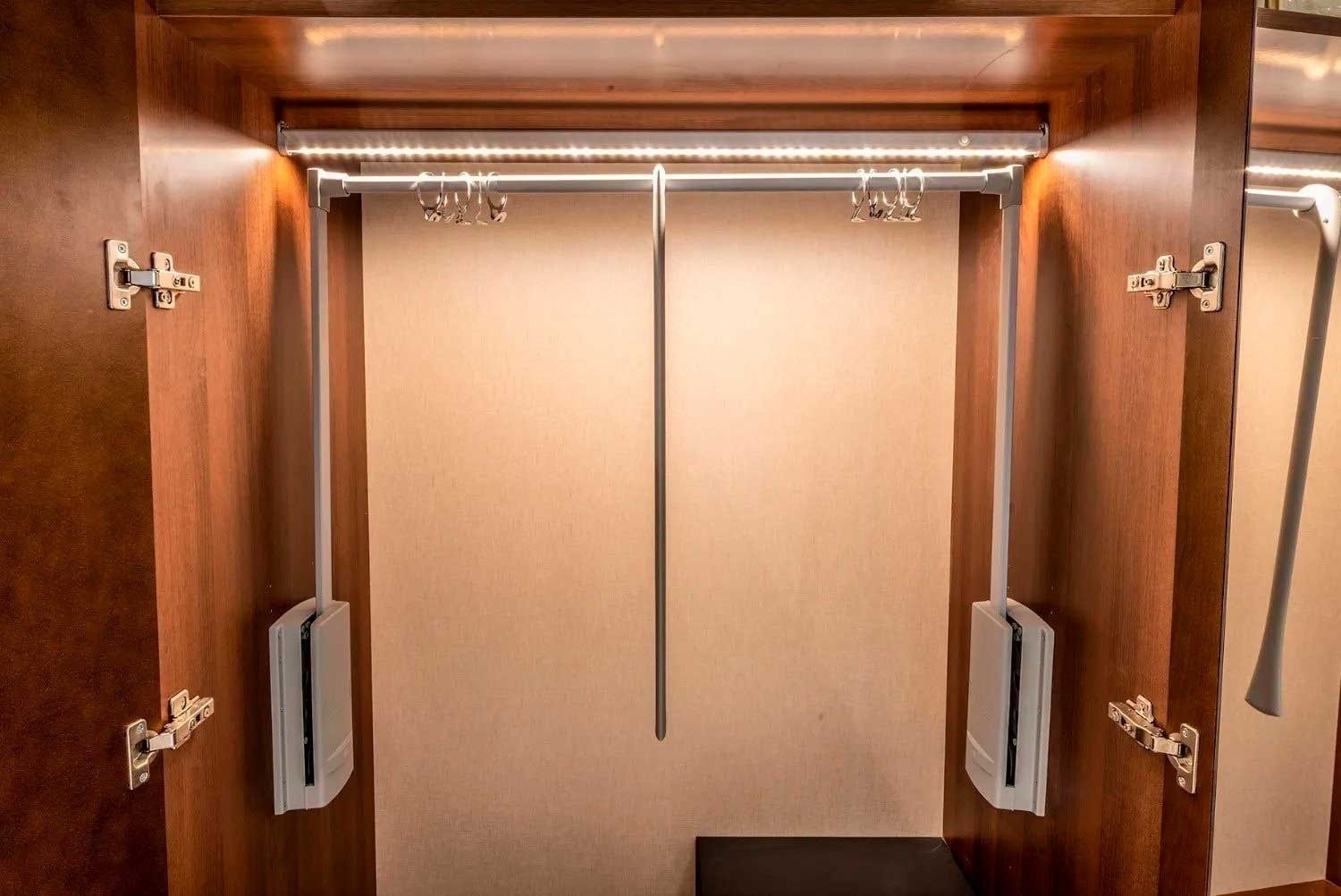 a closet with clothes hanging on a rack and a light on