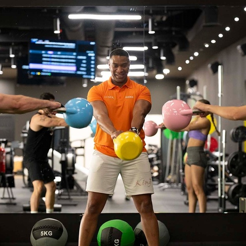 un hombre con una camisa naranja sostiene una bola de 5 kg