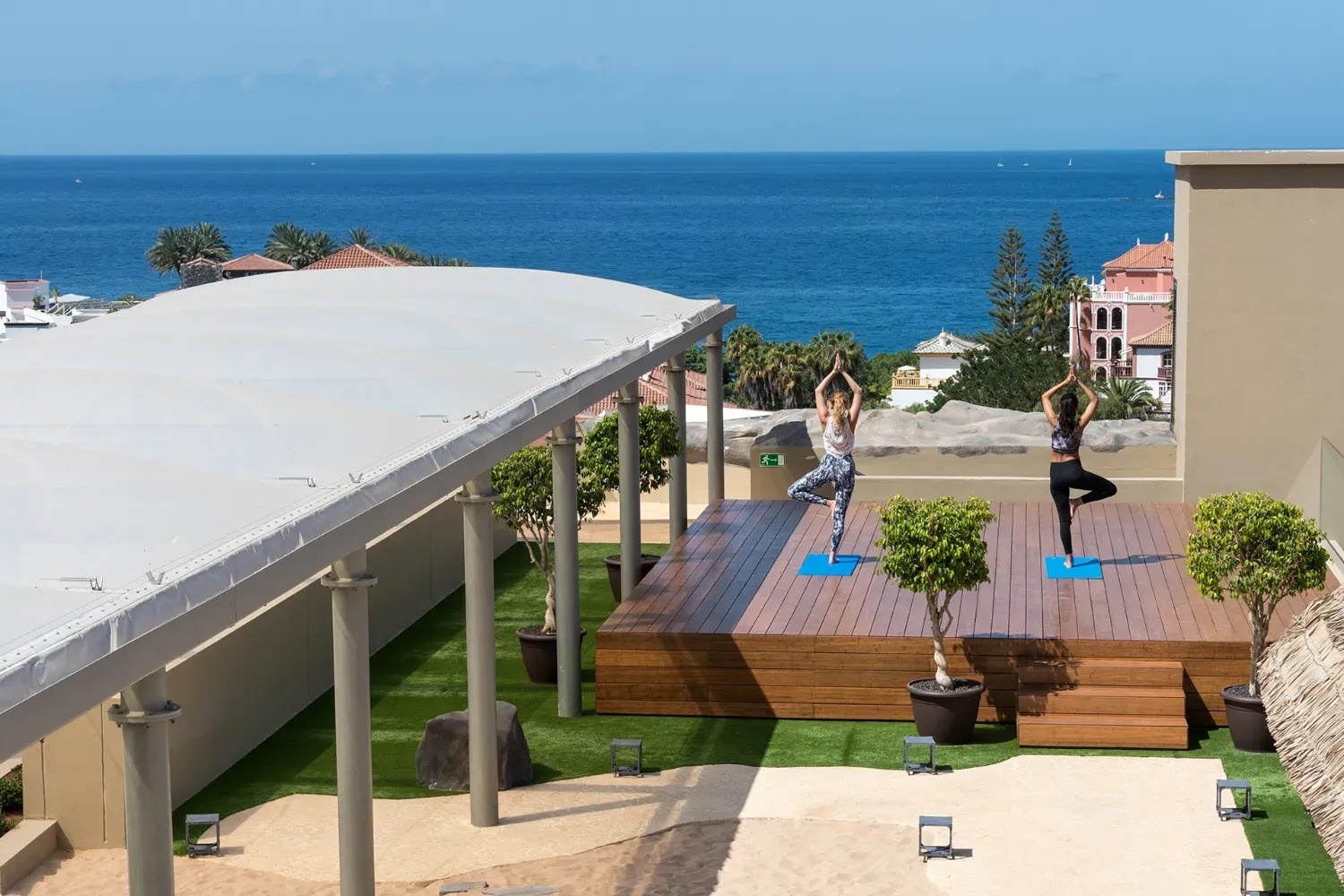 dos mujeres están practicando yoga en un escenario con vistas al océano
