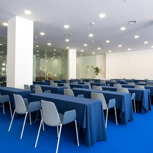 una sala de conferencias con mesas y sillas y una alfombra azul