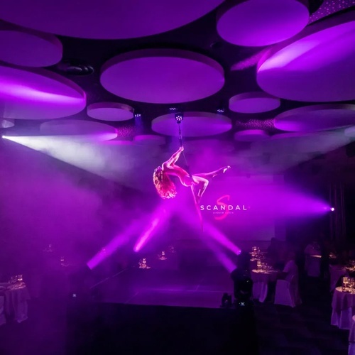 un artista aéreo actúa en un escenario con la palabra scandal en el fondo