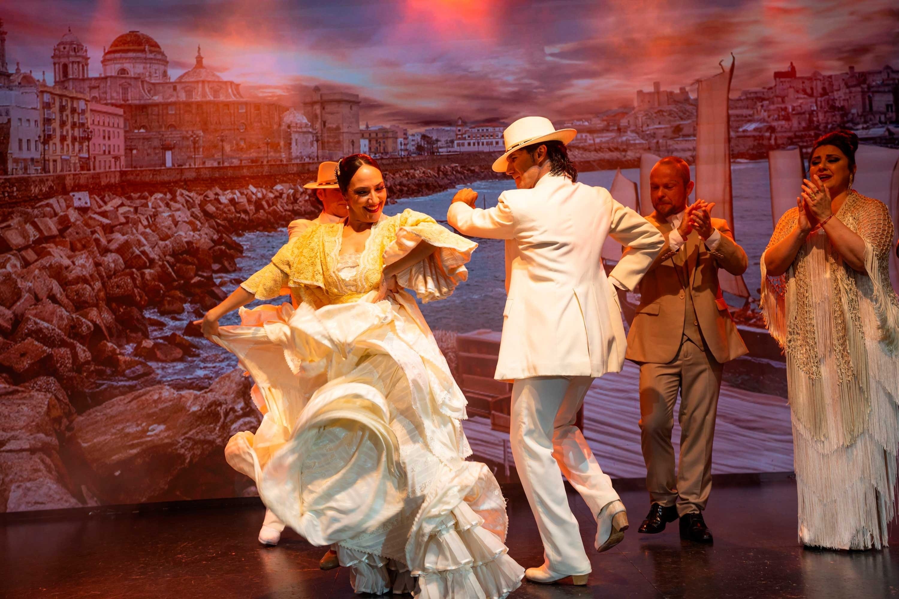 un grupo de hombres y mujeres en vestidos blancos con lunares rojos están actuando en un escenario