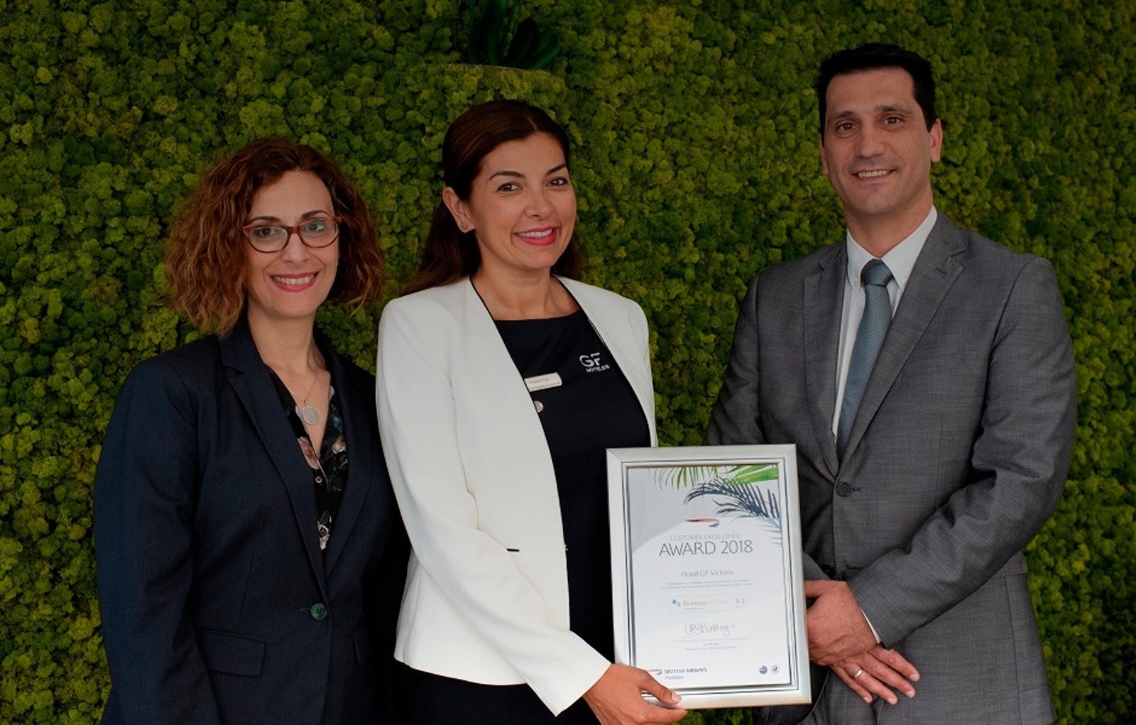 un hombre y dos mujeres sostienen un premio de 2018