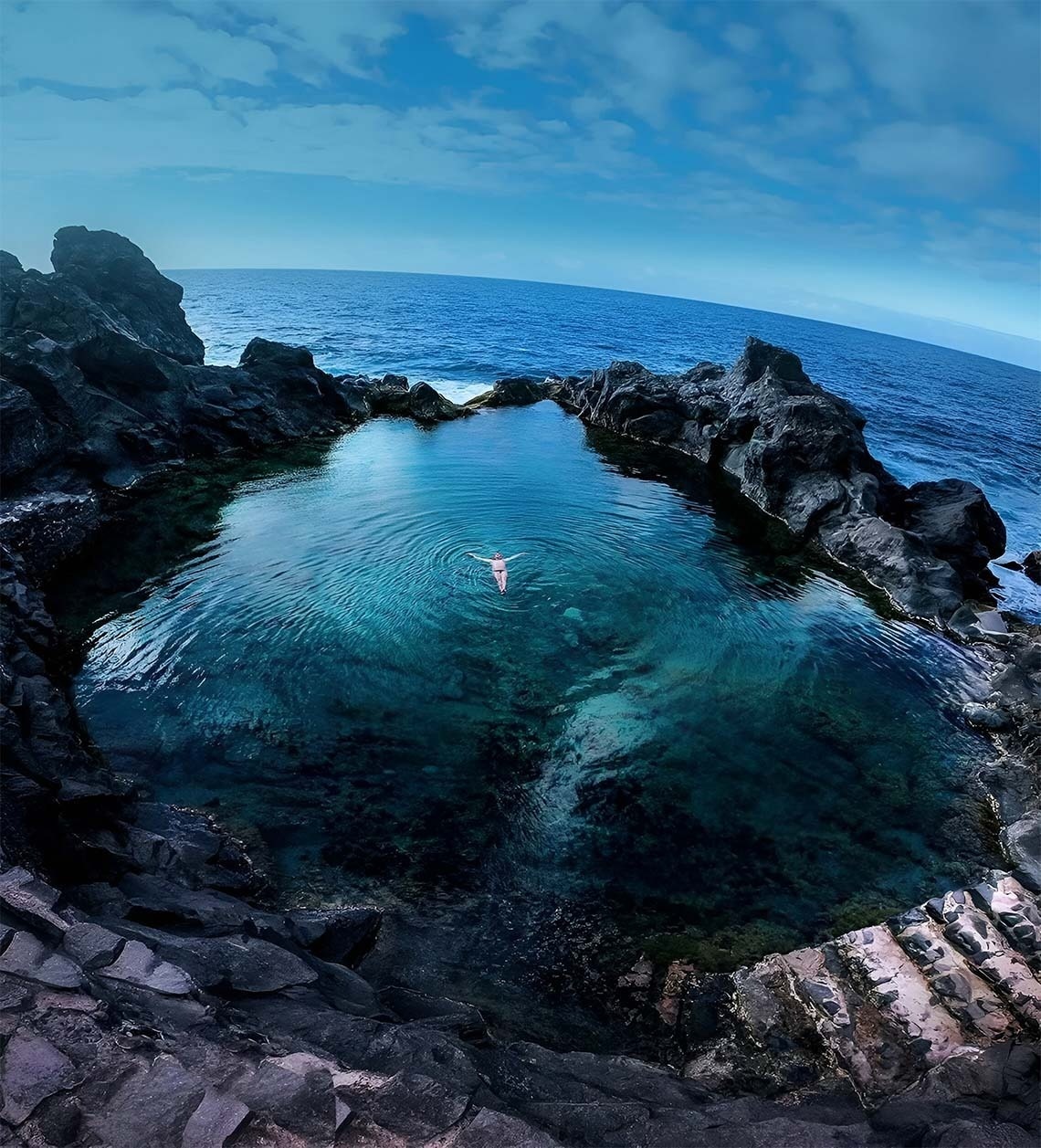 a person is swimming in a pool of water surrounded by rocks