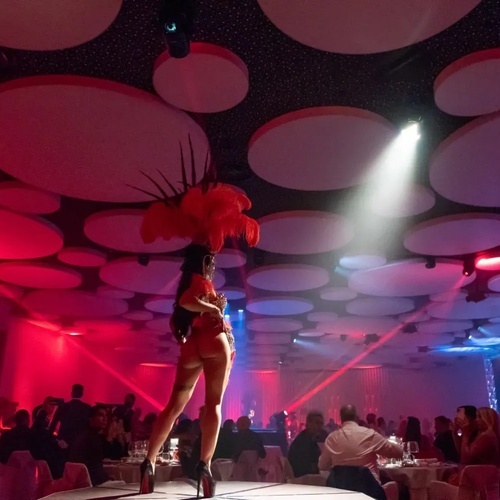 una mujer con plumas en la cabeza baila en una habitación llena de gente