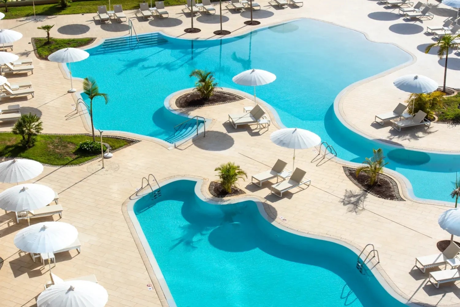 a large swimming pool surrounded by chairs and umbrellas