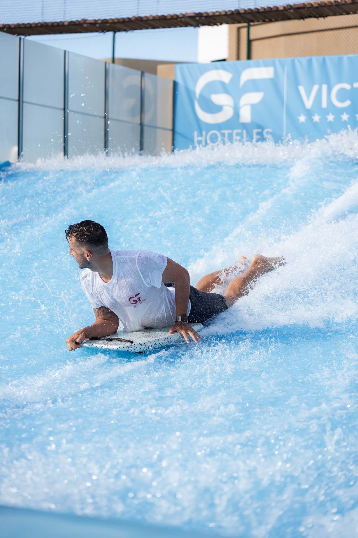 a man laying on a surfboard in front of a sign that says gf hoteles