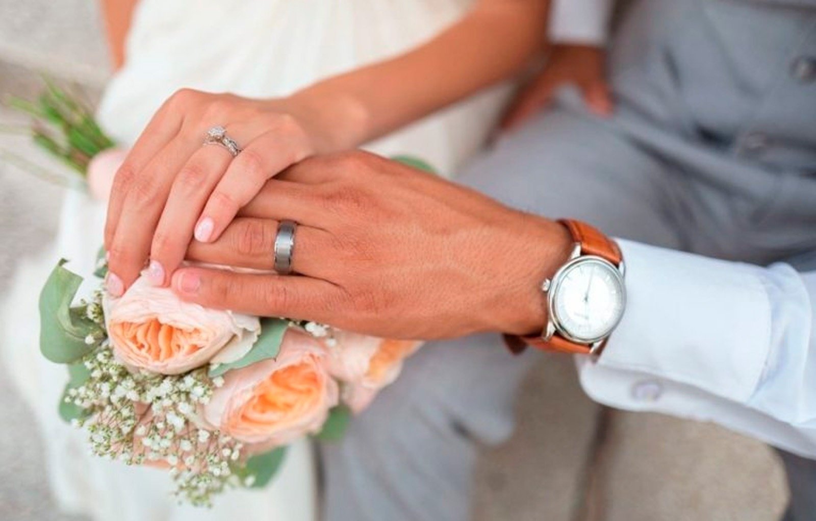 a bride and groom holding hands with their wedding rings on