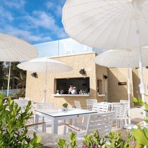 un restaurante con mesas y sillas y paraguas blancos