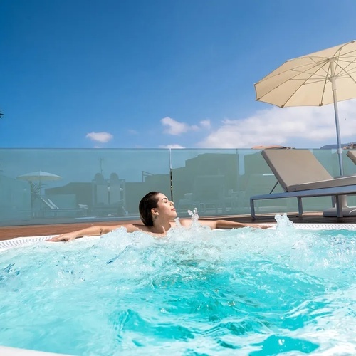 una mujer se sienta en una bañera de hidromasaje con un paraguas al fondo