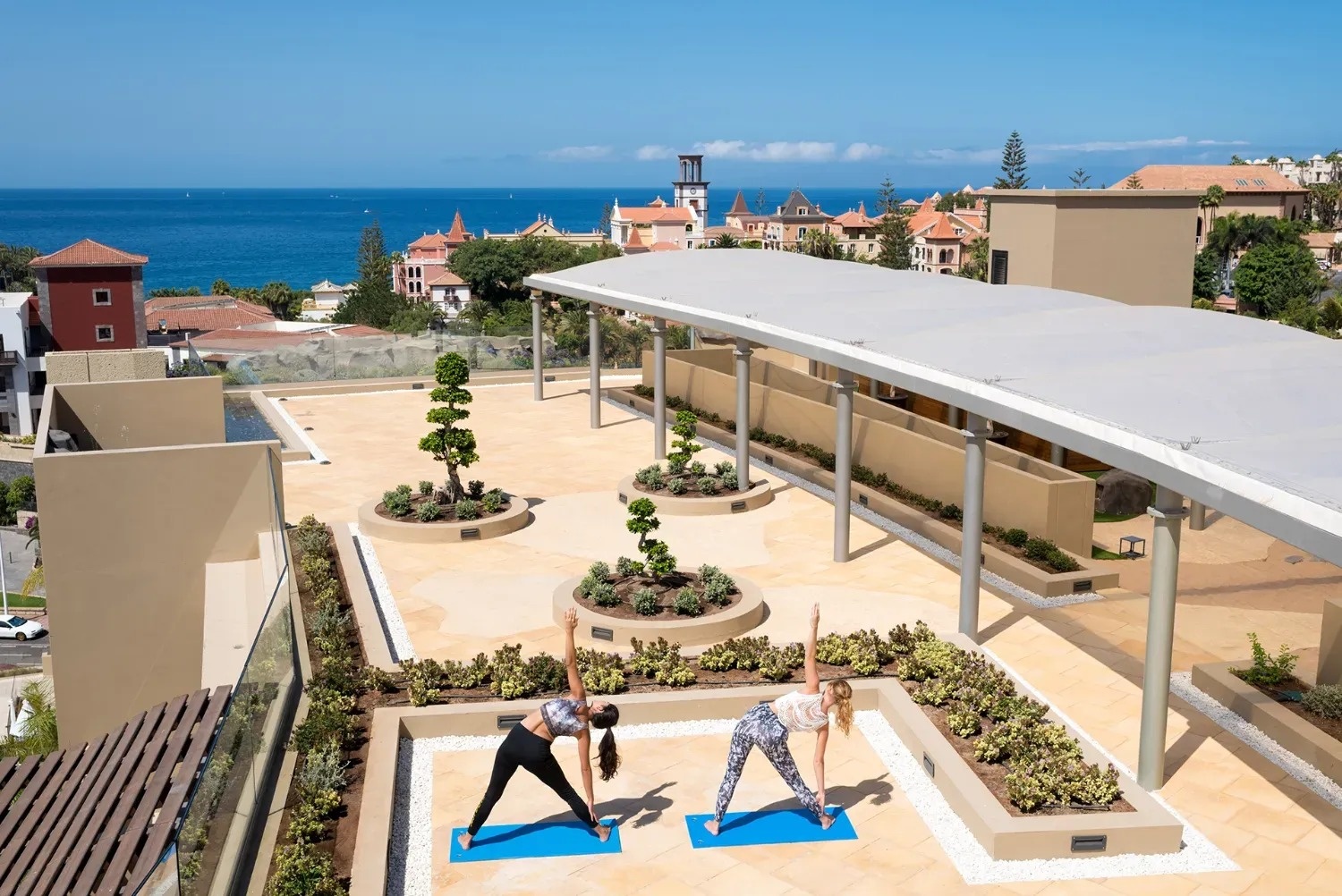 dos mujeres están practicando yoga en el techo de un edificio