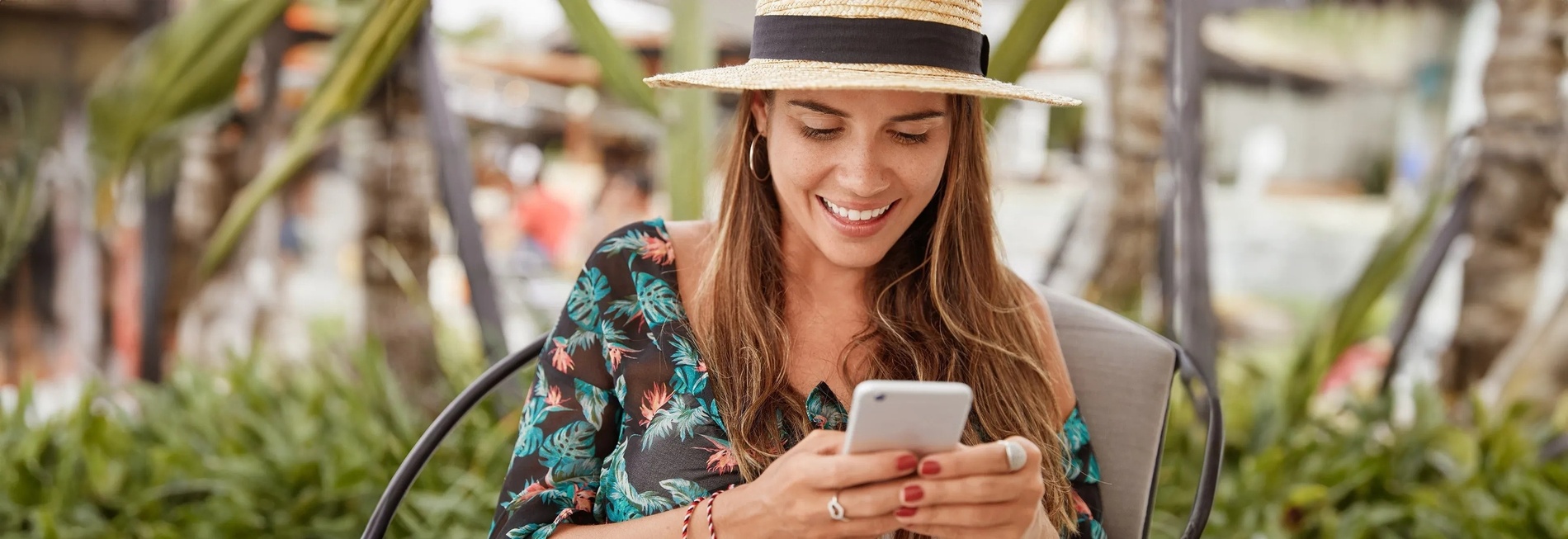 a woman wearing a straw hat is smiling while looking at her phone