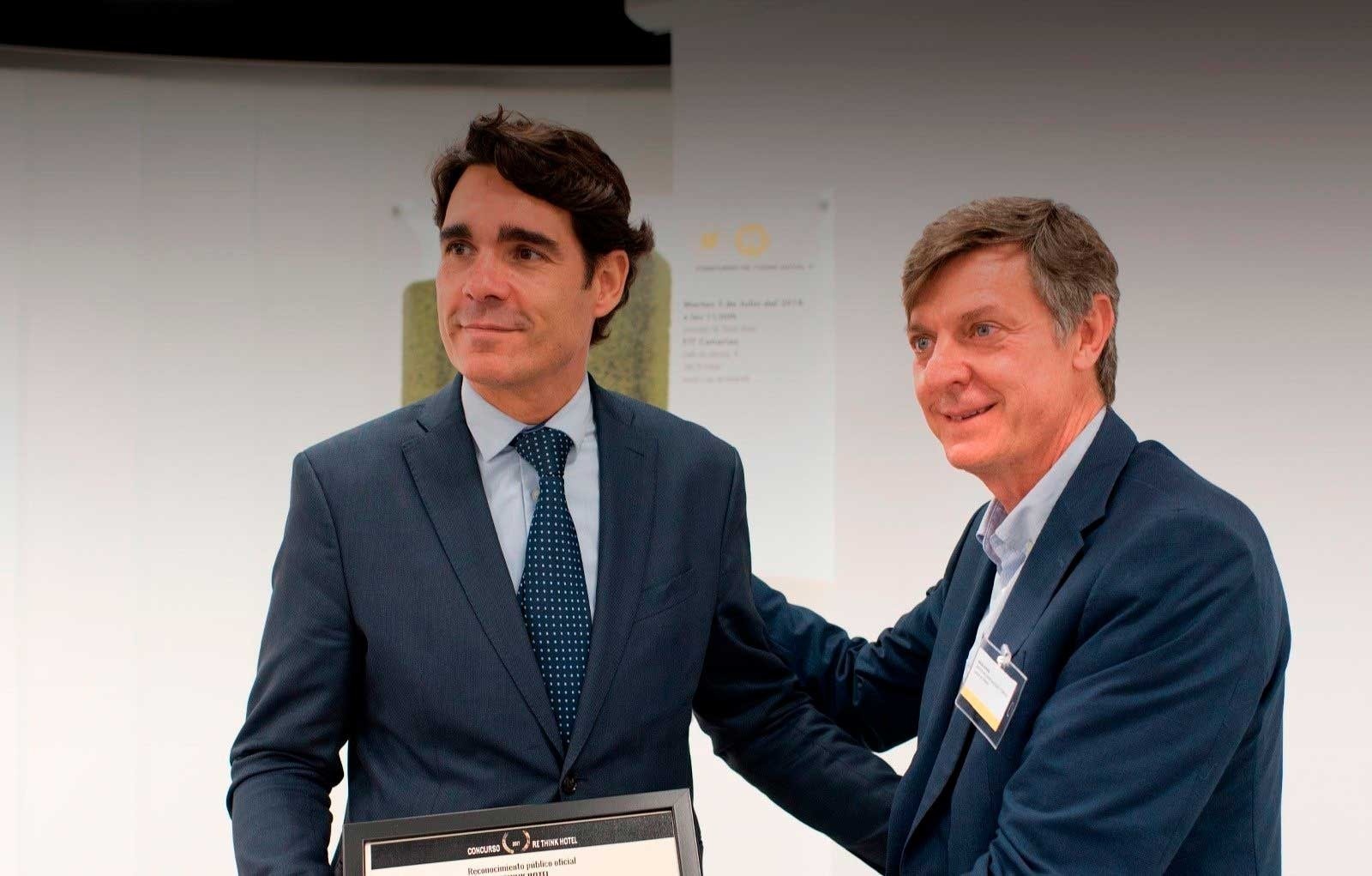 two men shaking hands with one holding a certificate that says ' premio a la excelencia ' on it